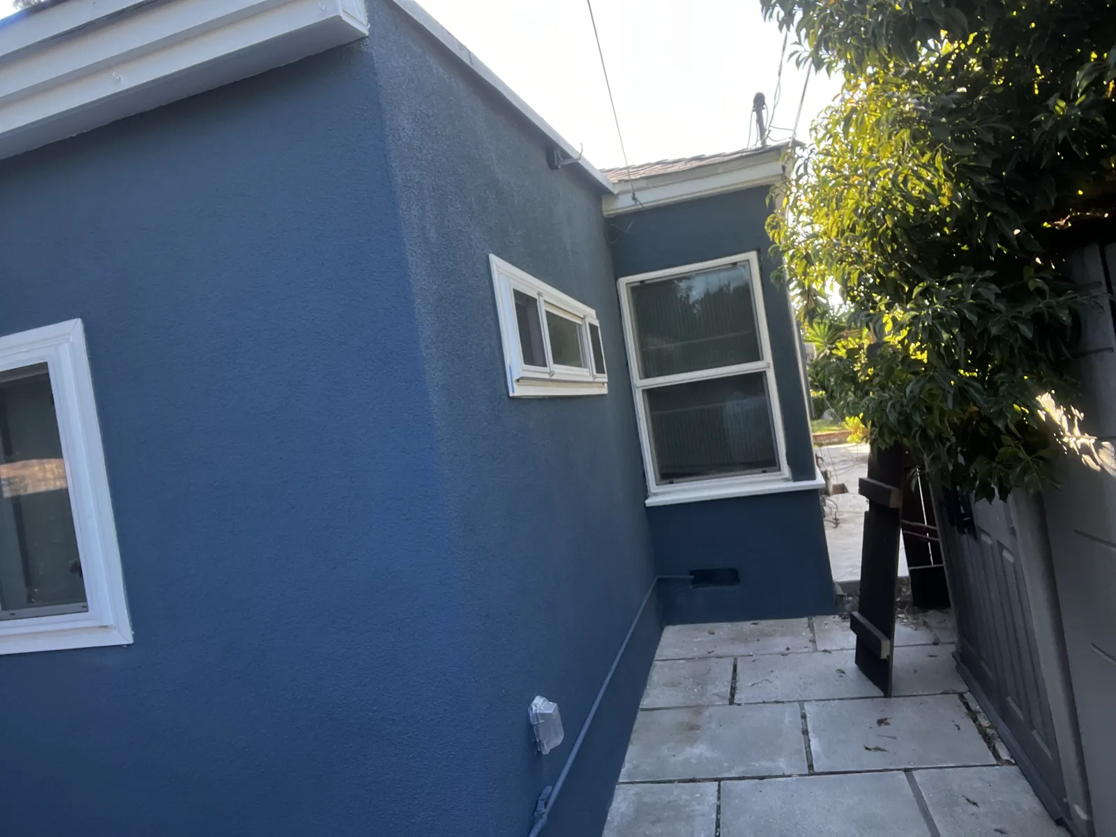 Finished blue stucco exterior with white window trim after repair and repaint