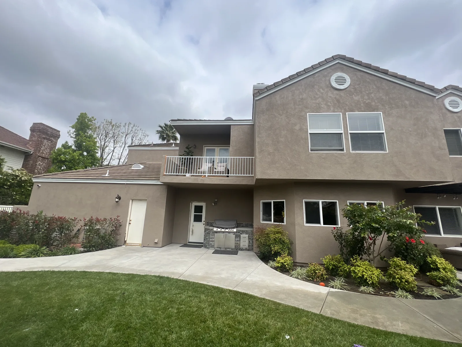 Large two-story stucco home in Arcadia with tile roof and balcony after repainting
