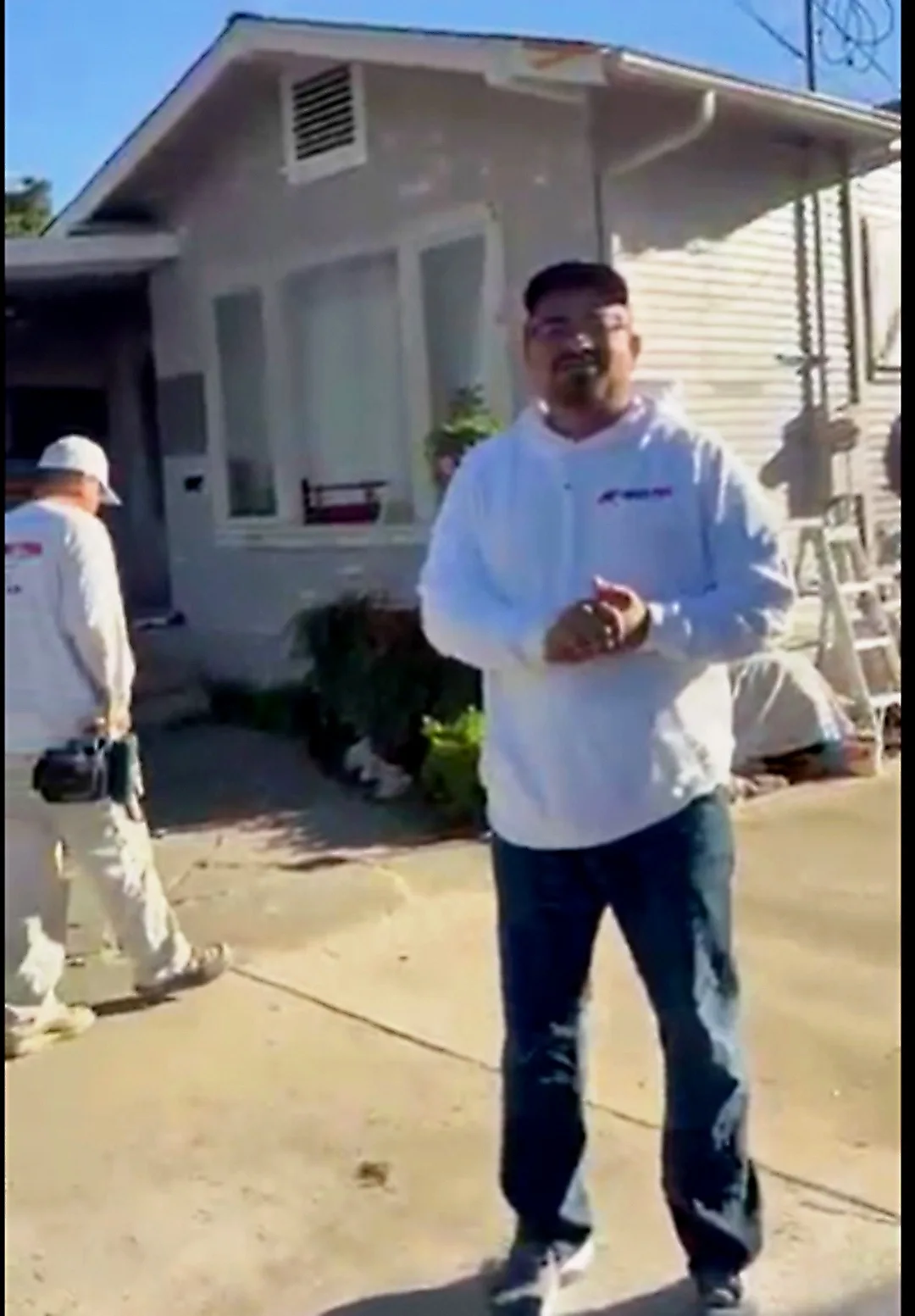 Ivan Martinez of Ivan's Pro Painting on a job site with his crew working behind him